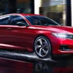 A red 2021 Honda Accord is driving on a wet city street.