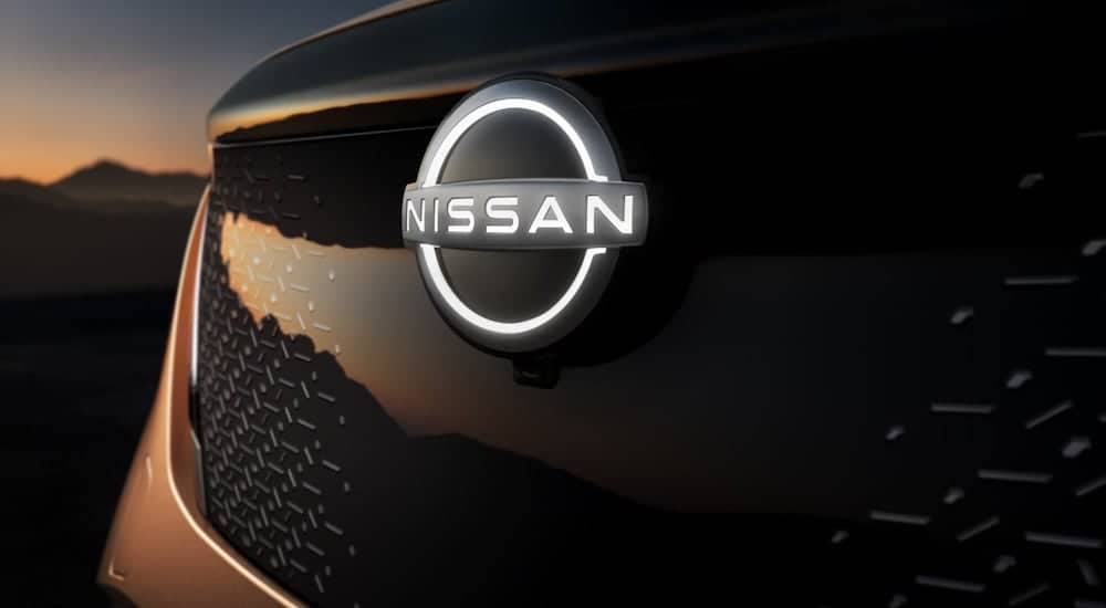 A close up shows the illuminated front Nissan emblem on a Nissan Ariya.