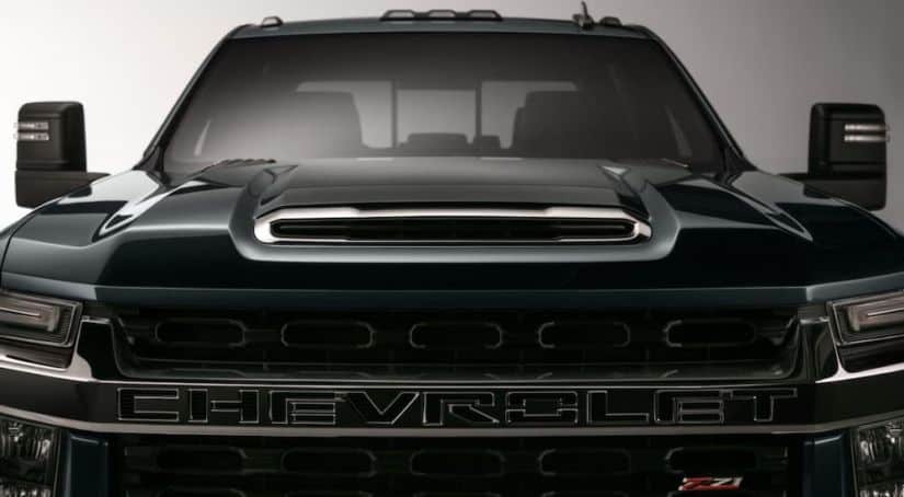 A closeup shows the silhouette on a black 2020 pre-owned Chevy 3500HD from the front against a gray background.