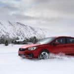 A red 2020 Subaru Impreza is shown driving in the snow after leaving a Subaru dealer near you.