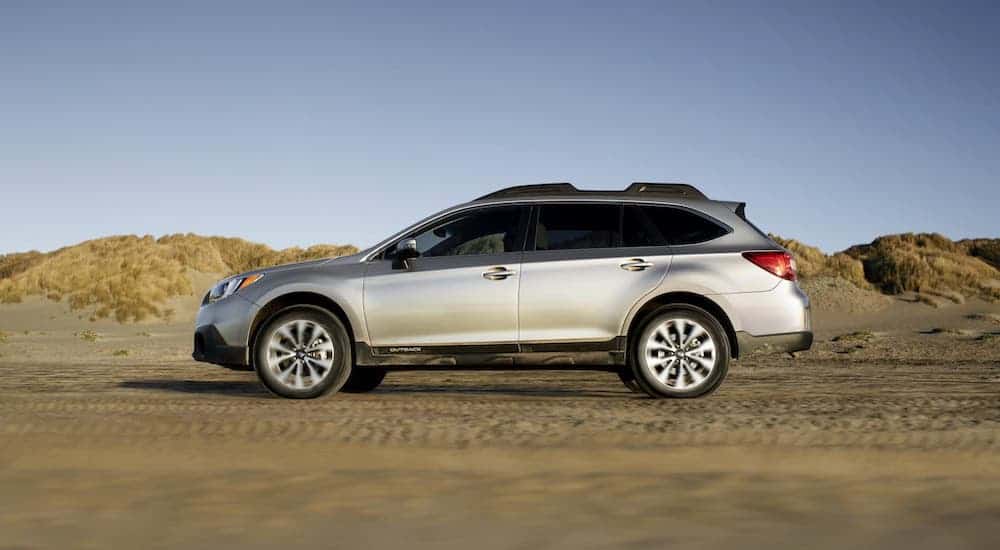A silver 2019 Subaru Outback is shown from the side driving in a desert.
