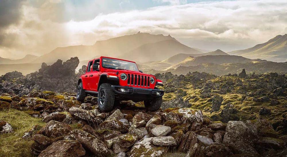 A red 2018 Jeep Wrangler Unlimited is climbing over rocks.
