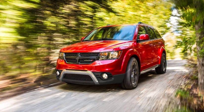 A red 2020 Dodge Journey is speeding through a wooded road.