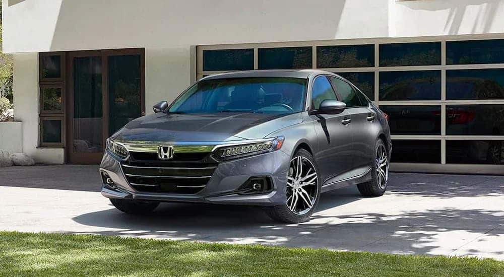 A gray 2021 Honda Accord is parked in front of a modern garage.