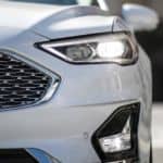 A closeup shows the grille of a white 2020 Ford Fusion as part of the 2020 Ford Fusion vs 2021 Toyota Camry comparison.