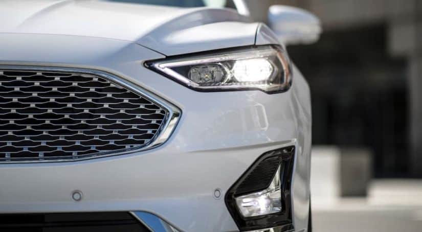 A closeup shows the grille of a white 2020 Ford Fusion as part of the 2020 Ford Fusion vs 2021 Toyota Camry comparison.
