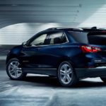 A dark blue 2021 Chevy Equinox is shown parked at an angle in a warehouse after winning a 2021 Chevy Equinox vs 2021 Mazda CX-5 comparison.