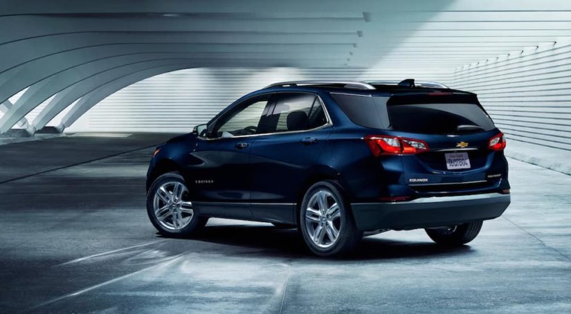 A dark blue 2021 Chevy Equinox is shown parked at an angle in a warehouse after winning a 2021 Chevy Equinox vs 2021 Mazda CX-5 comparison.