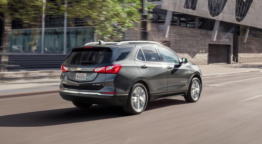 A silver 2021 Chevy Equinox is shown from the back driving in a city.