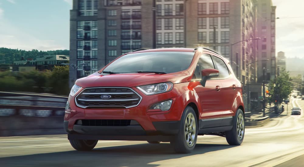 A red 2021 Ford EcoSport is driving in an urban area. 