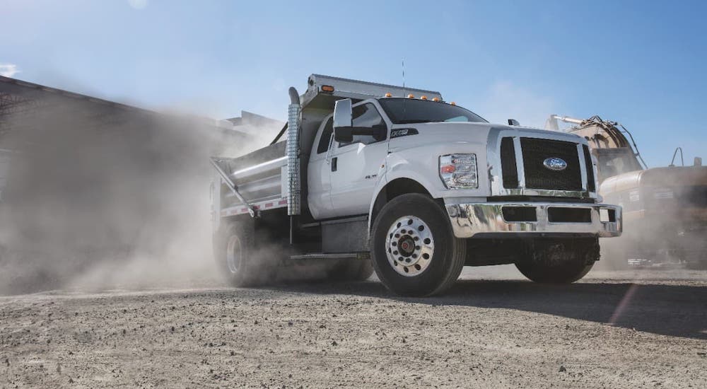 A white 2021 Ford F-750 Dump Truck is parked at a dusty construction site.