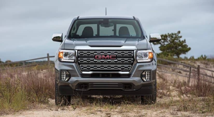 A gray 2021 GMC Canyon is shown from the front with a fence in the background.