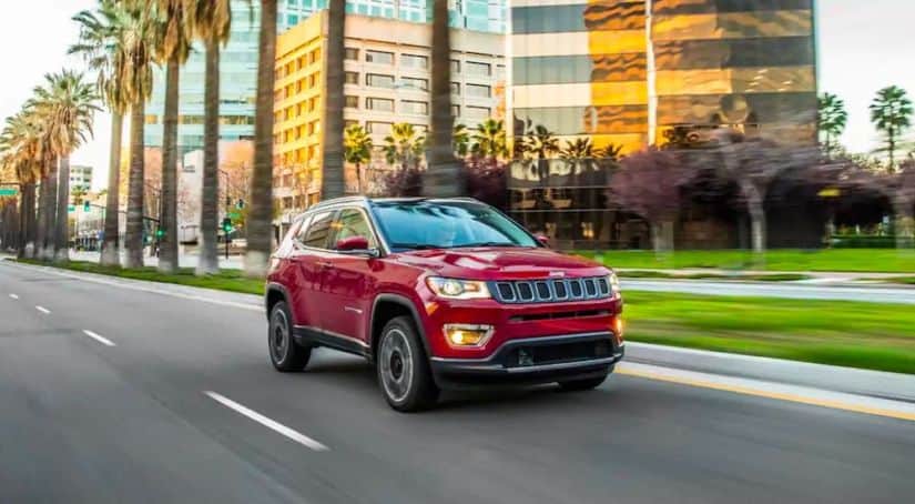 A red 2021 Jeep Compass is driving on a city street.