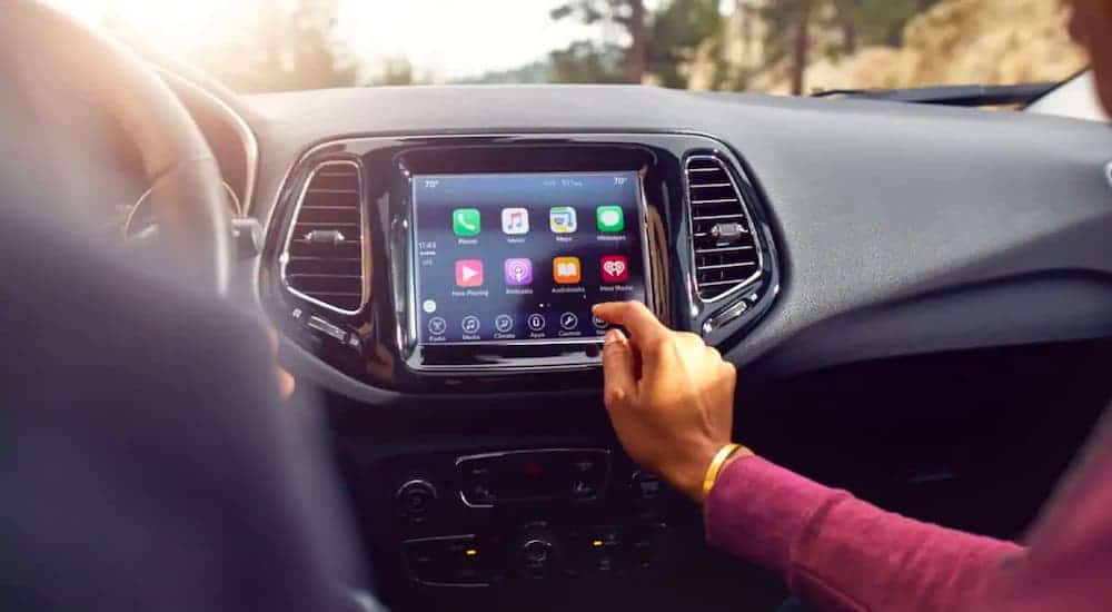 A passenger in a 2021 Jeep Compass is using the infotainment screen.