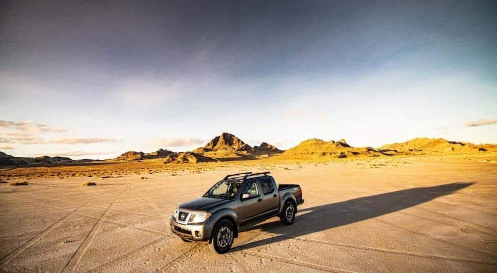 A gray 2021 Nissan Frontier PRO-4x is parked in a desert in front of mountains.
