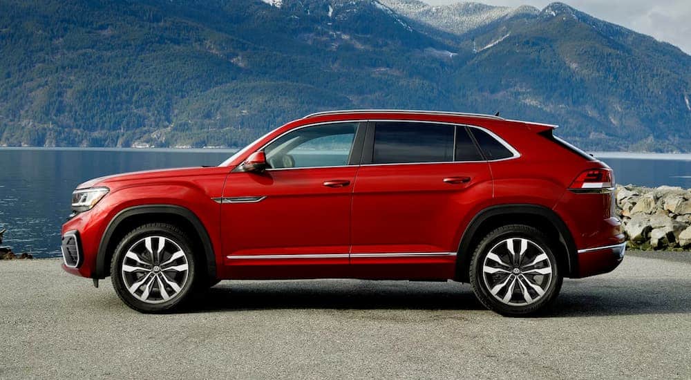 A red 2021 Volkswagen Atlas Cross Sport is shown from the side in front of mountains.