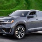 A grey 2021 Volkswagen Atlas Cross Sport is in front of green grass.