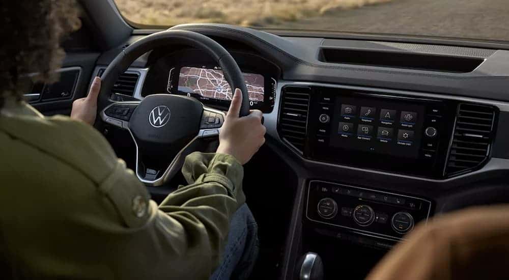 An interior view shows a person driving with navigation on the dash in a 2021 Volkswagen Atlas Cross Sport.