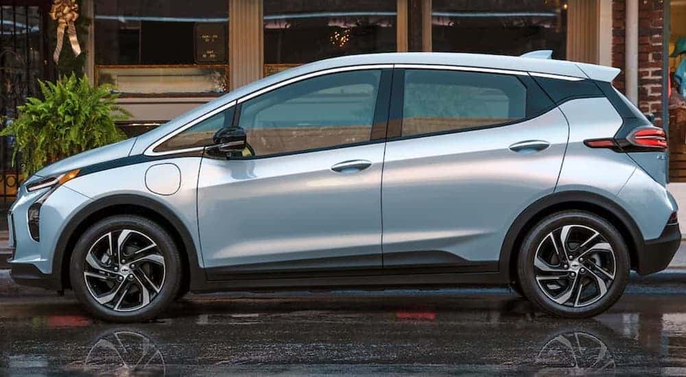 A light blue 2022 Chevy Bolt EV is shown from the side on a city street.