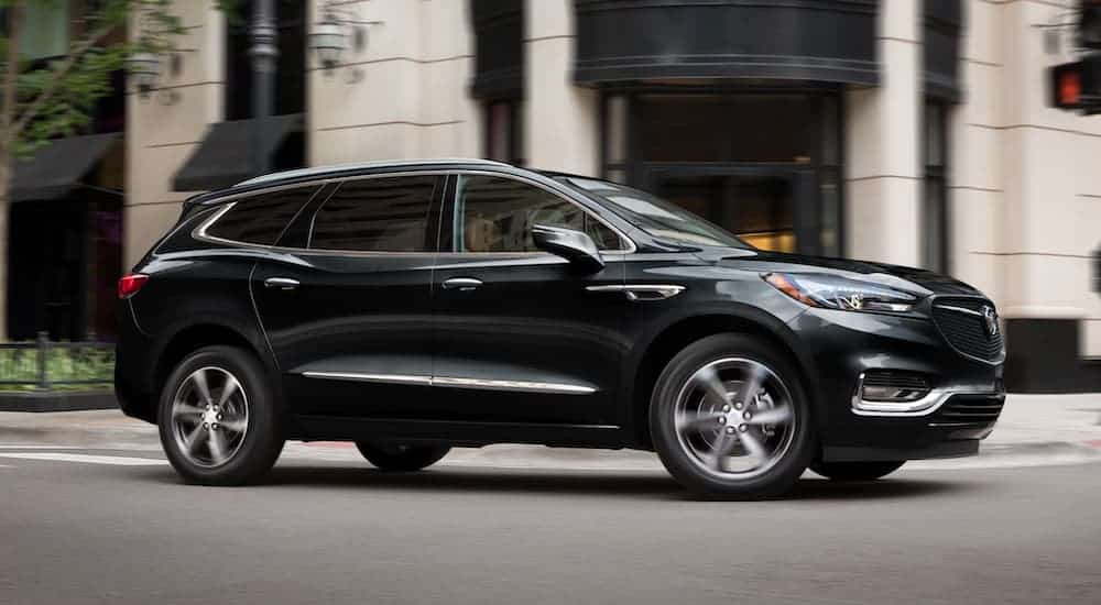 A black 2021 Buick Enclave is shown driving through a city.