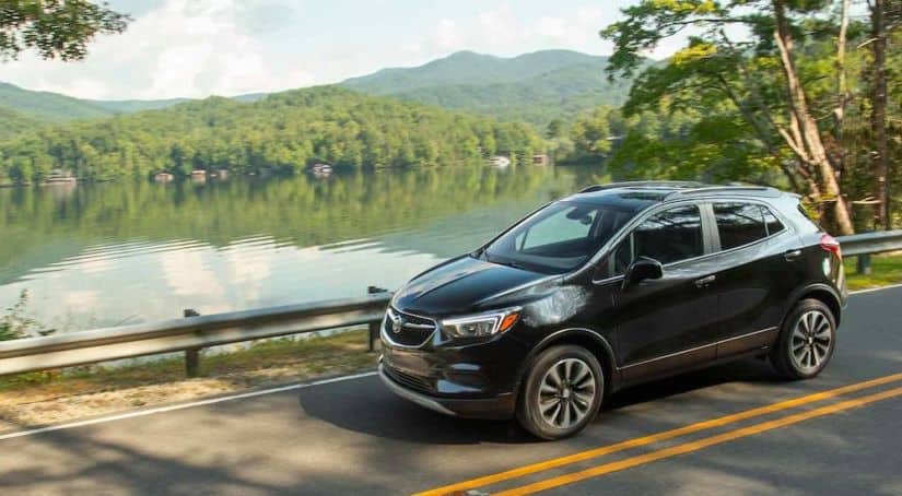 A black 2021 Buick Encore is shown driving past a lake.