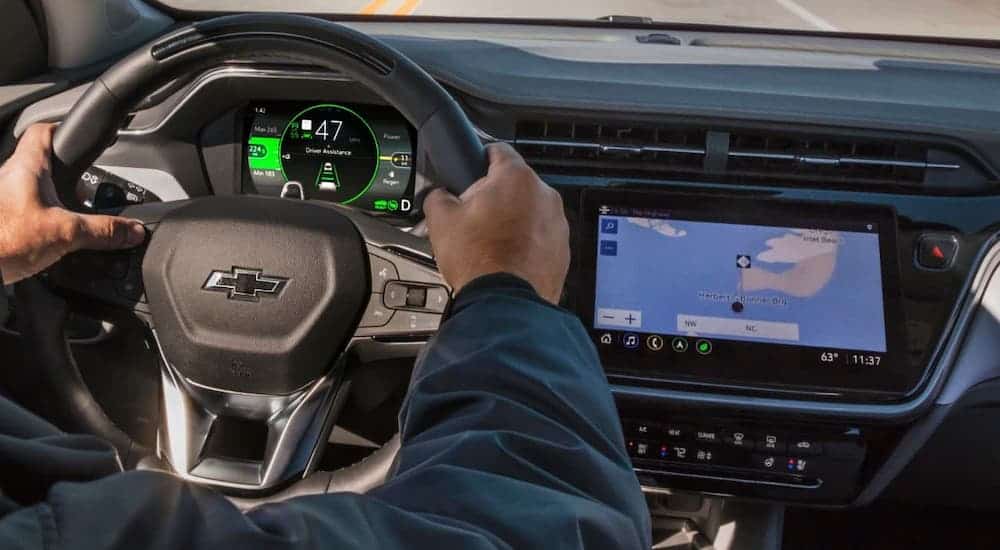 A closeup shows the steering wheel and infotainment screen in a 2022 Chevy Bolt EUV while someone is driving.