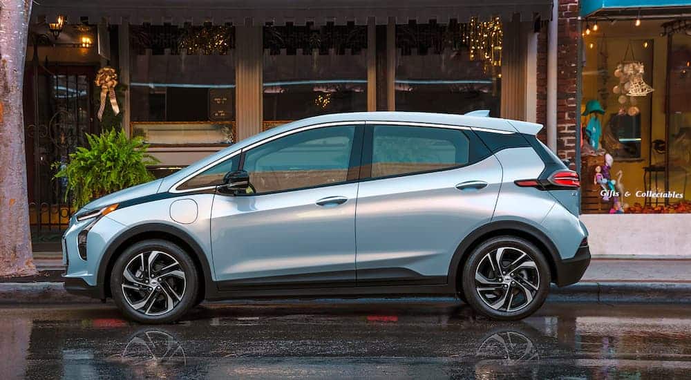 A popular Chevy EV, a silver 2022 Chevy Bolt EV, is shown from the side parked parked in front of a collectible shop.