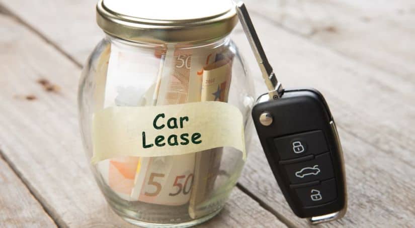 A close up shows a jar full of money labeled car lease.