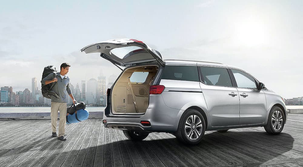 A silver 2021 Kia Sedona is shown from the side with the lift gate open.