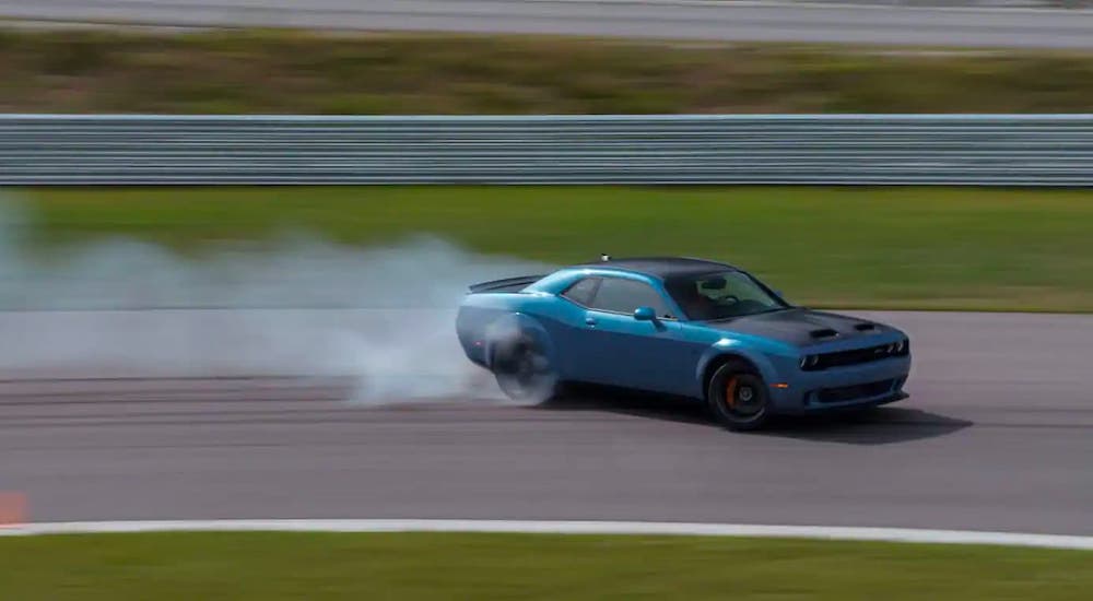 A blue 2021 Dodge Challenger is drifting on a race track.