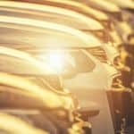 A close up shows a row of cars at sunset.
