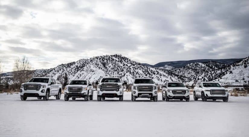 The lineup of 2021 AT4 GMC models are shown in white in front of mountains in the snow.