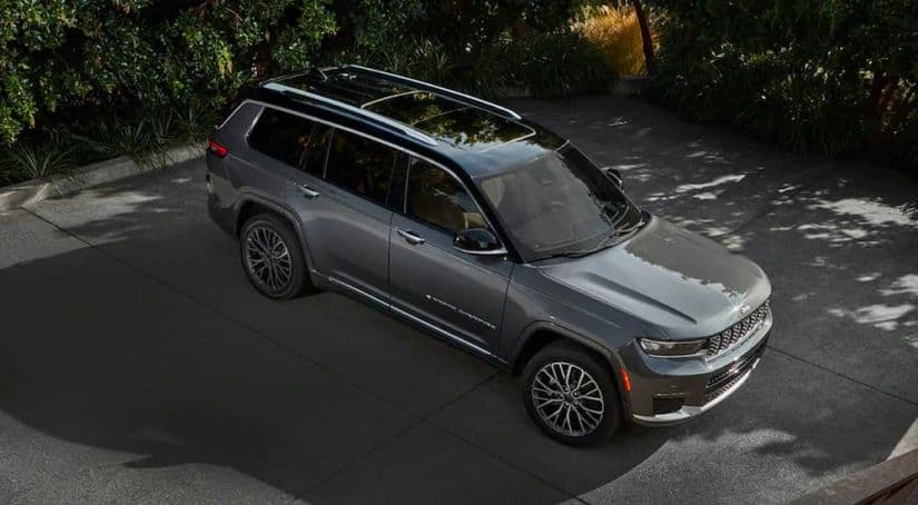 A dark gray 2021 Jeep Grand Cherokee L is shown from a high angle parked in an empty lot.