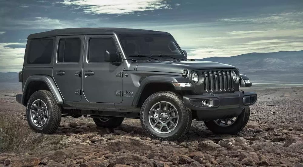 A gray 2021 Jeep Wrangler Unlimited Anniversary edition is parked in front of distant mountains.