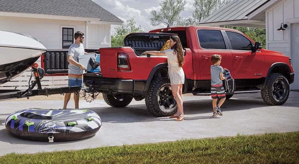 A red 2019 Ram 1500 is parked with a boat attached to its tow hitch.