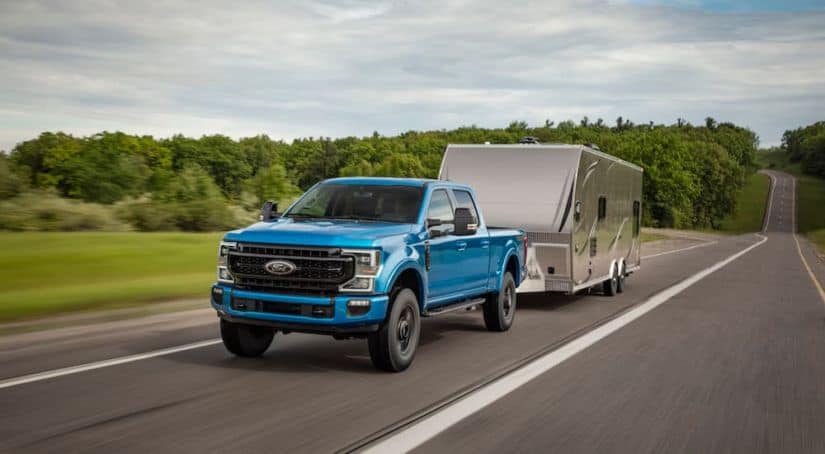 A blue 2020 Ford F-250 Super Duty Tremor is towing a trailer down the highway.