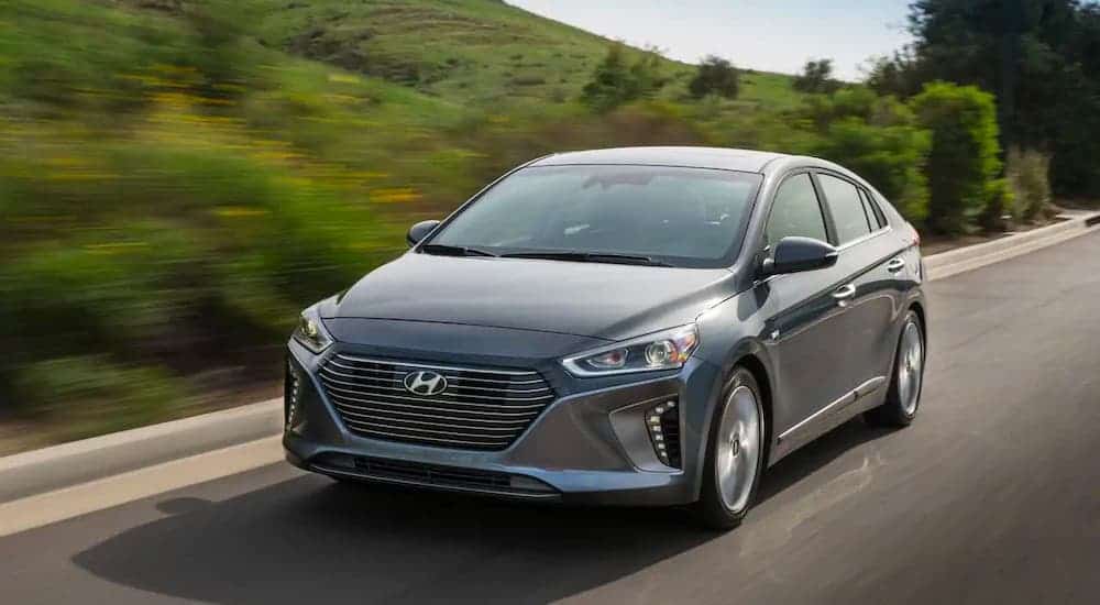 A gray 2017 Hyundai Ioniq is driving on a highway past blurred hills.