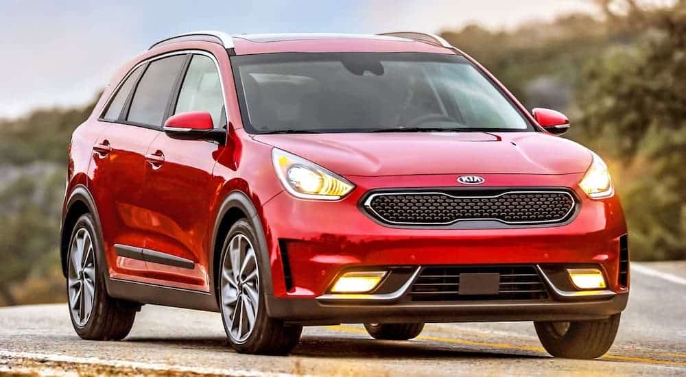 A red 2017 Kia Niro is driving on a blurred highway.