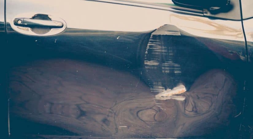Something to look out for when shopping for used cars in Fort Worth, a close up shows a door dent on a vehicle.