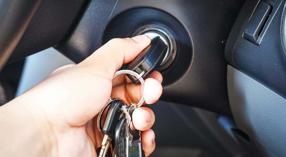 A close up shows a hand inserting keys into an ignition.