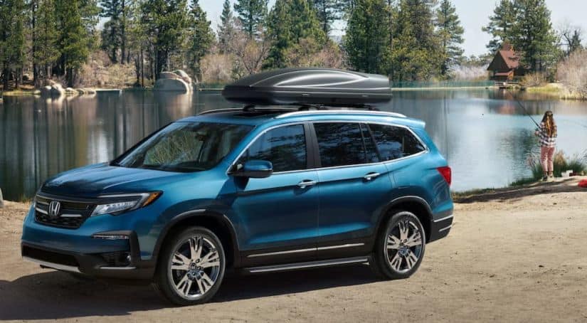 A blue 2020 used Honda Pilot is shown from the side parked next to a lake.