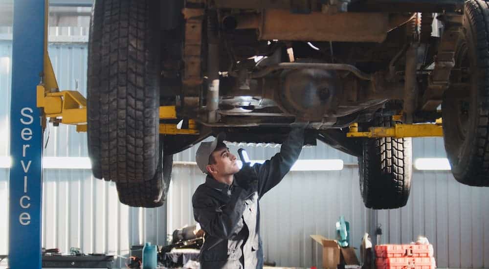 A mechanic is shown inspecting an SUV on a lift.