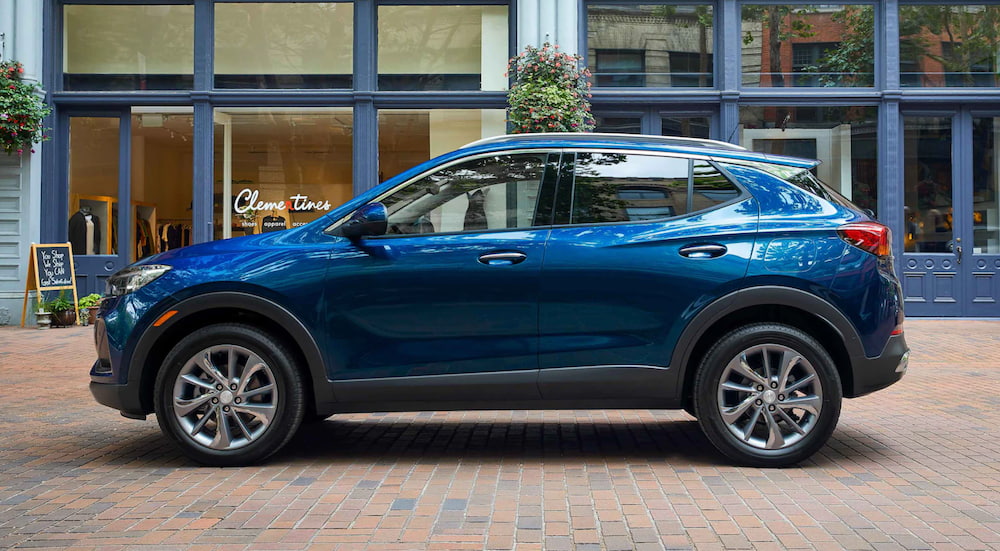 A blue 2021 Buick Encore GX is parked outside of a shopping area.
