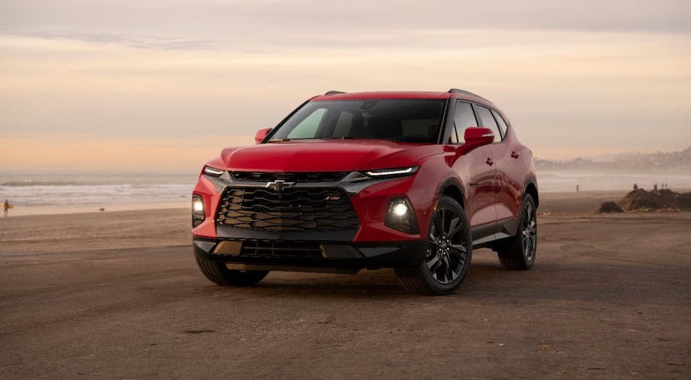 A red 2021 Chevy Blazer RS is parked on a beach at sunset.