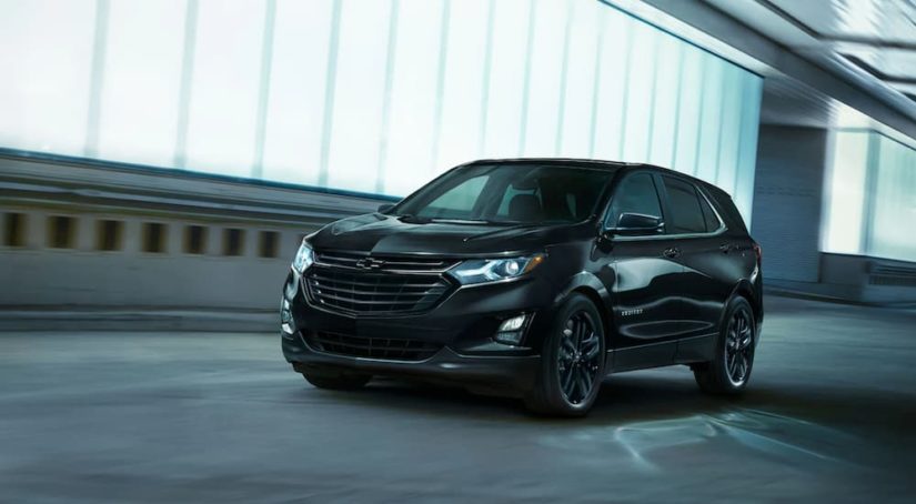 A black 2021 Chevy Equinox is shown from an angle parked in a warehouse.