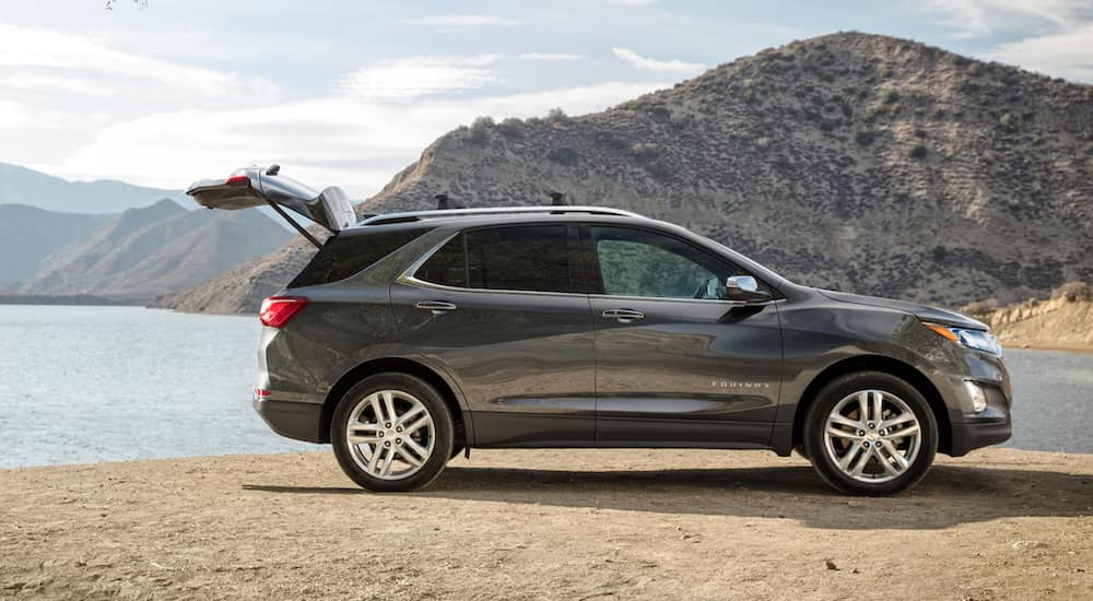 A dark grey 2021 Chevy Equinox is parked in front of a lake with the lift gate open.