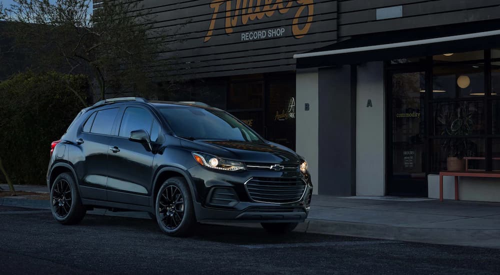 A black 2021 Chevy Trax is parked outside of a records store at dusk.