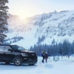 A black 2021 Ford Expedition STX is parked in the snow with mountains in the background.