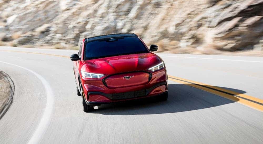 A red 2021 Ford Mustang Mach-E is shown from the front driving on a winding road after winning the 2021 Ford Mustang Mach-E vs 2022 Chevy Bolt EUV comparison.