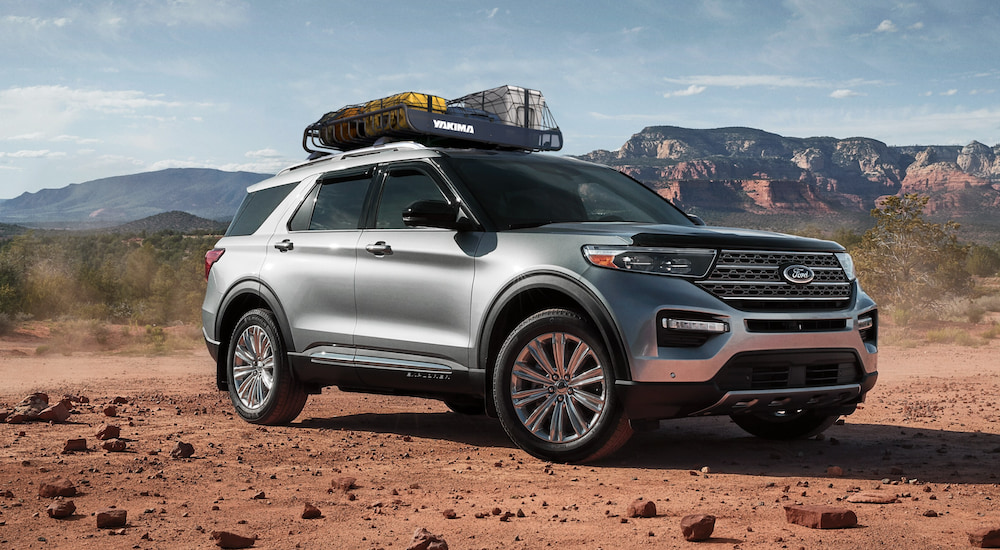 A silver 2021 Ford Explorer is parked in a red desert in front of mountains.